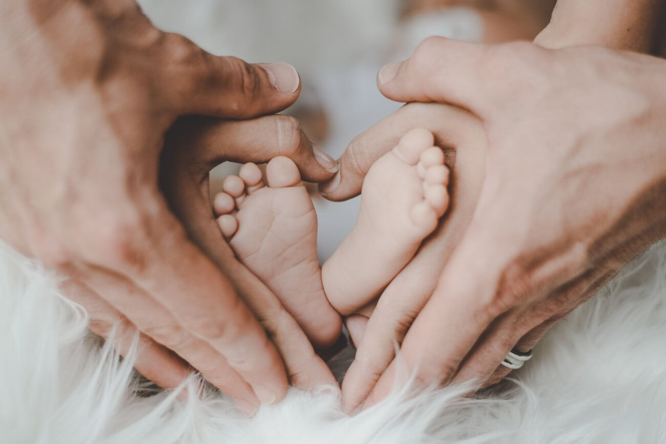 Padre y madre sosteniendo los pies de su bebé